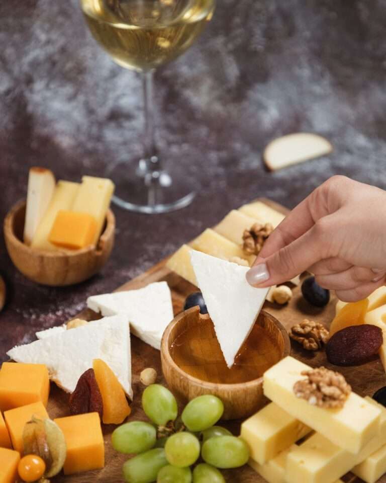 Assorted gourmet cheese platter with honey and white wine pairing.